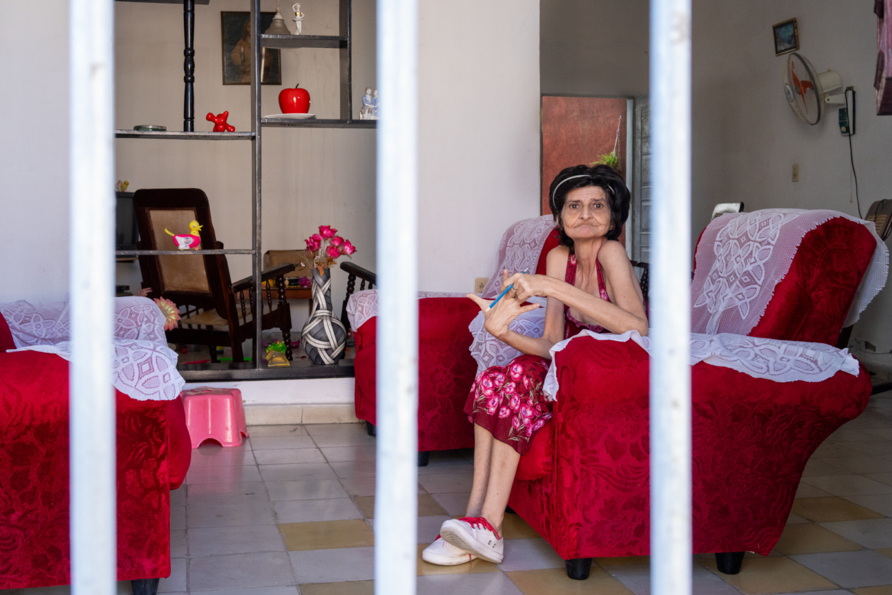 Cuba Street Photography Roadtrp | 14 Day Guide with Mark Seymour 7 “Intimate glimpse into a Cuban home as an elderly woman sits quietly in her red armchair behind the bars of her doorway.”