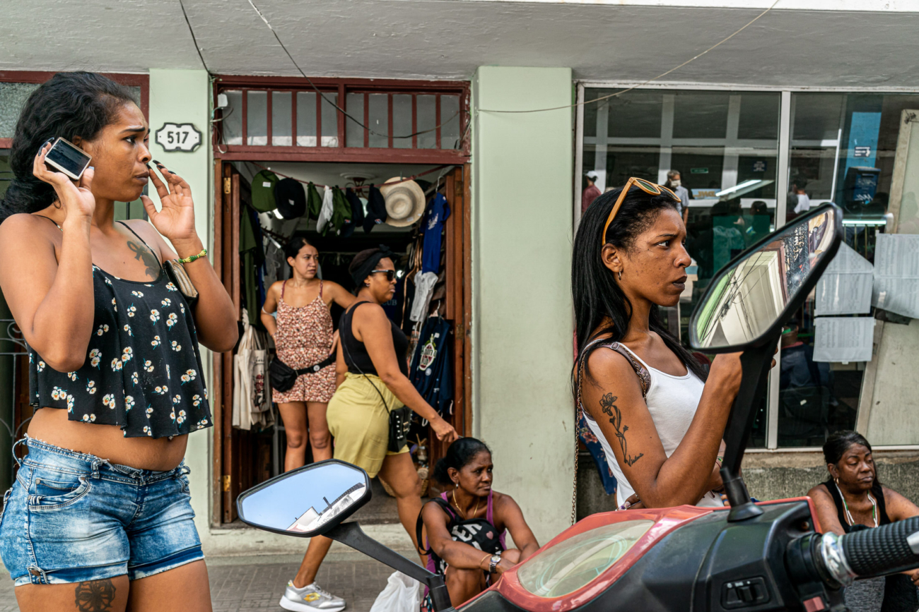 Cuba Street Photography Roadtrp | 14 Day Guide with Mark Seymour 12 “Women standing and chatting outside a small Cuban shop, with a scooter mirror reflecting the street in the foreground.”