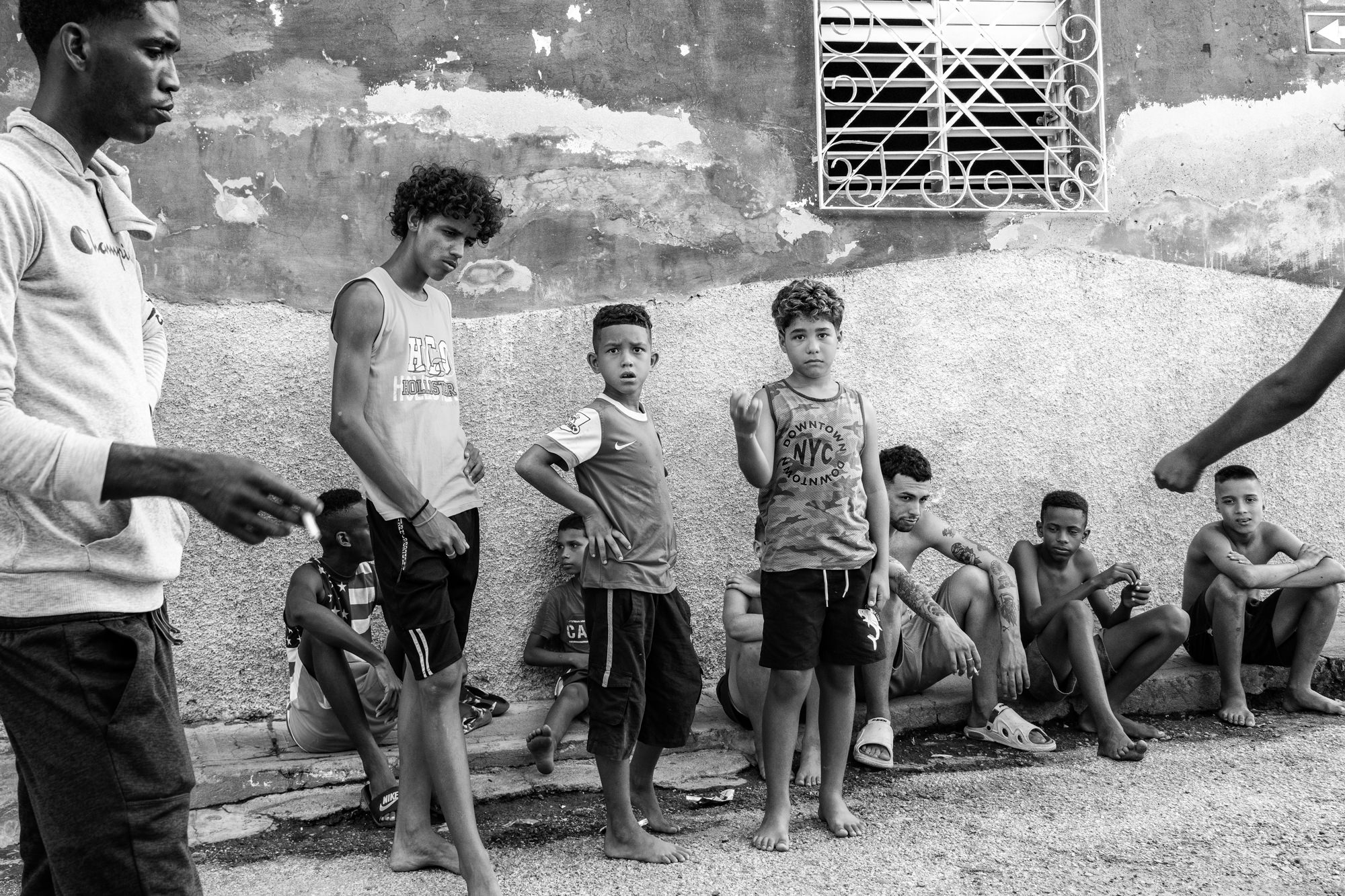 Cuba Street Photography Roadtrp | 14 Day Guide with Mark Seymour 27 “Energetic monochrome street scene of Cuban youth gathered casually along a faded wall.”