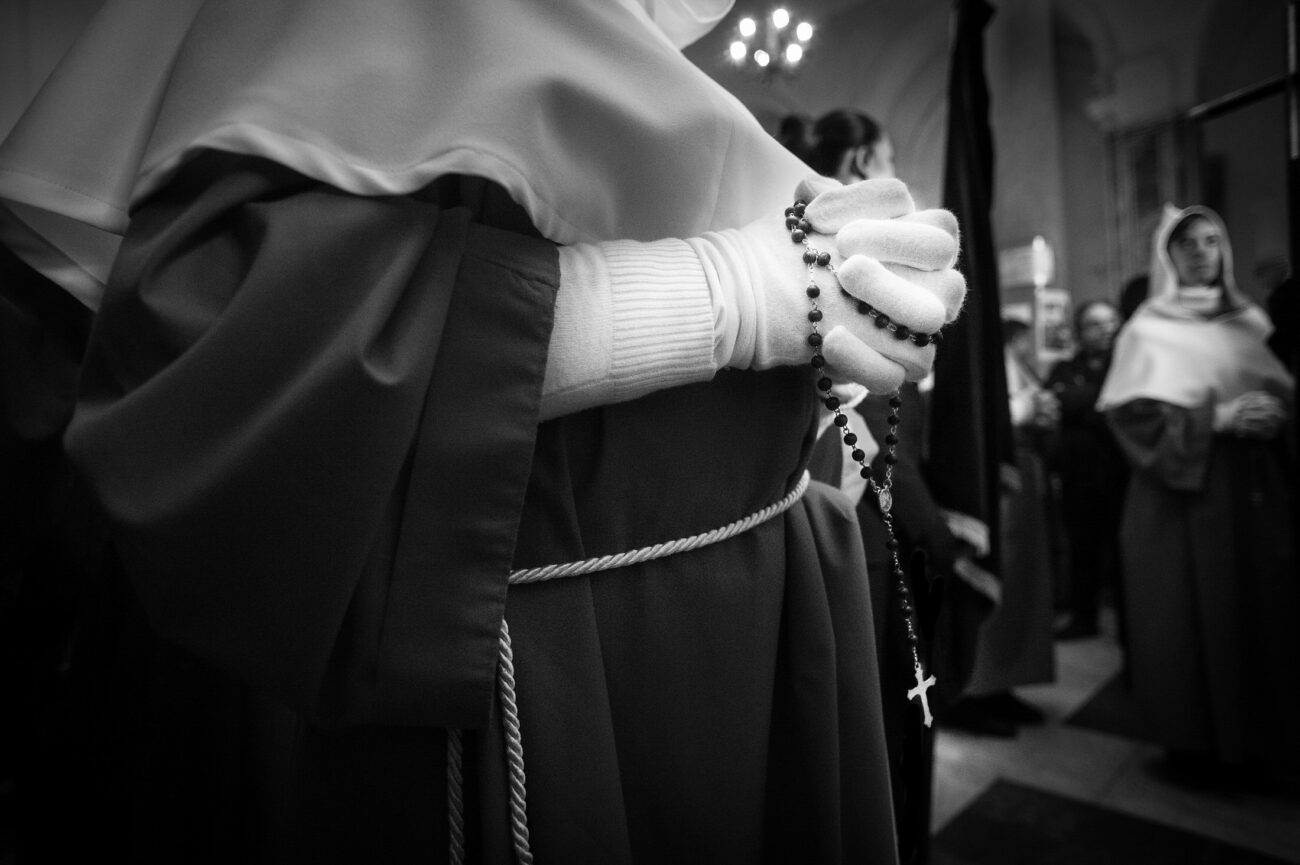 Inside the Misteri di Trapani: Documenting Sicily’s Living Tradition 8 A confraternity member holding a rosary inside the Church of the Anime Sante before the Misteri di Trapani procession begins in Trapani, Sicily.
