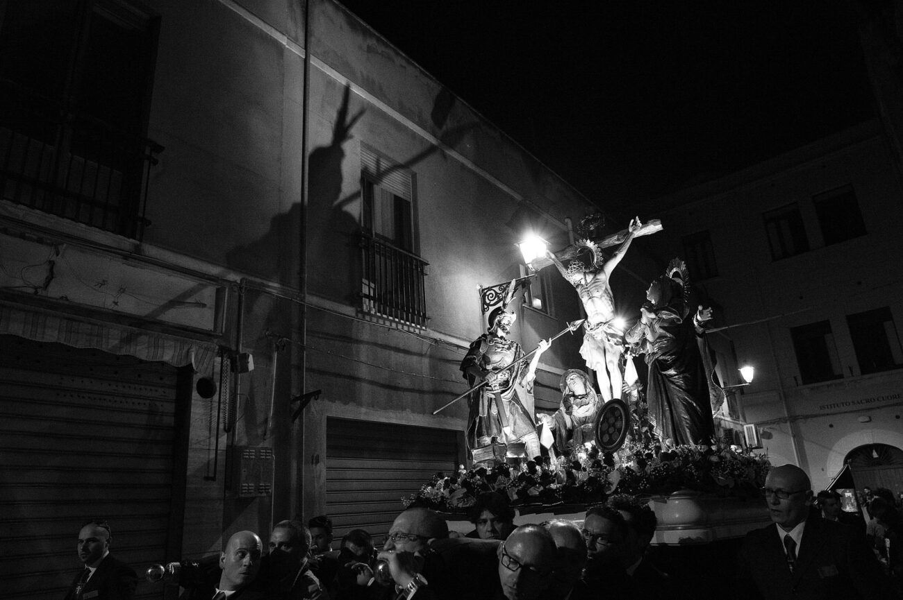 Inside the Misteri di Trapani: Documenting Sicily’s Living Tradition 16 The Crucifixion sacred group passes through the streets of Trapani after dark, casting the shadow of the cross onto a nearby building during the Misteri di Trapani procession.