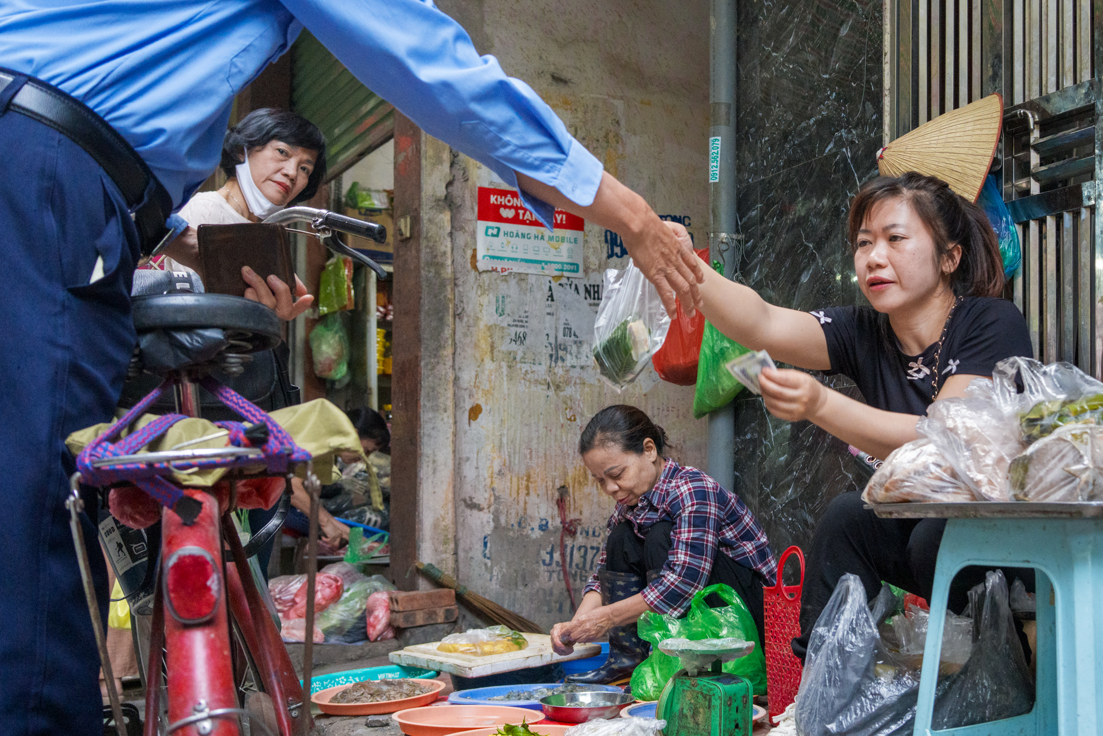 Northern Vietnam Photography: A Photographer’s Journey Beyond the Tourist Trail 26 A customer pays a street vendor at a neighbourhood market in Hanoi, Vietnam.