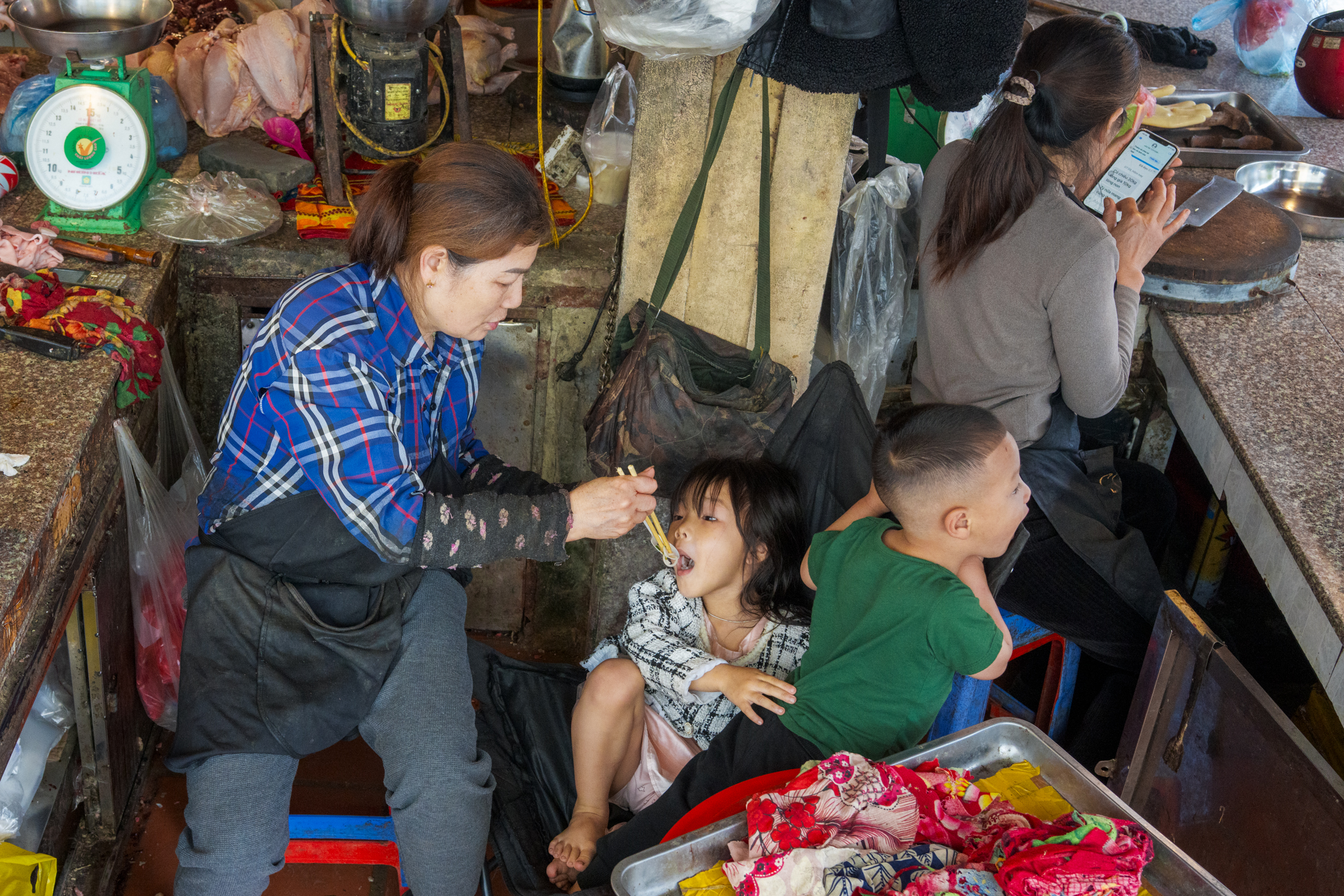 Northern Vietnam Photography: A Photographer’s Journey Beyond the Tourist Trail 11 A woman feeds a young child while working at a market stall in northern Vietnam.