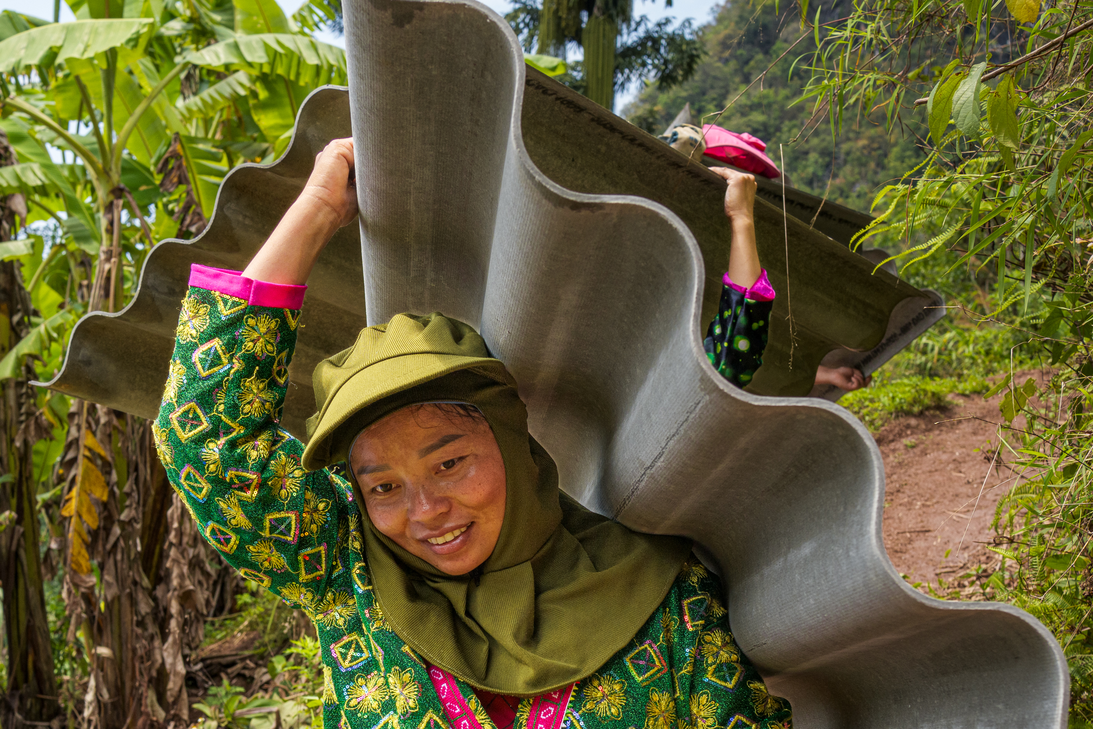 Northern Vietnam Photography: A Photographer’s Journey Beyond the Tourist Trail 21 A woman carries corrugated roofing sheets along a hillside path in northern Vietnam.