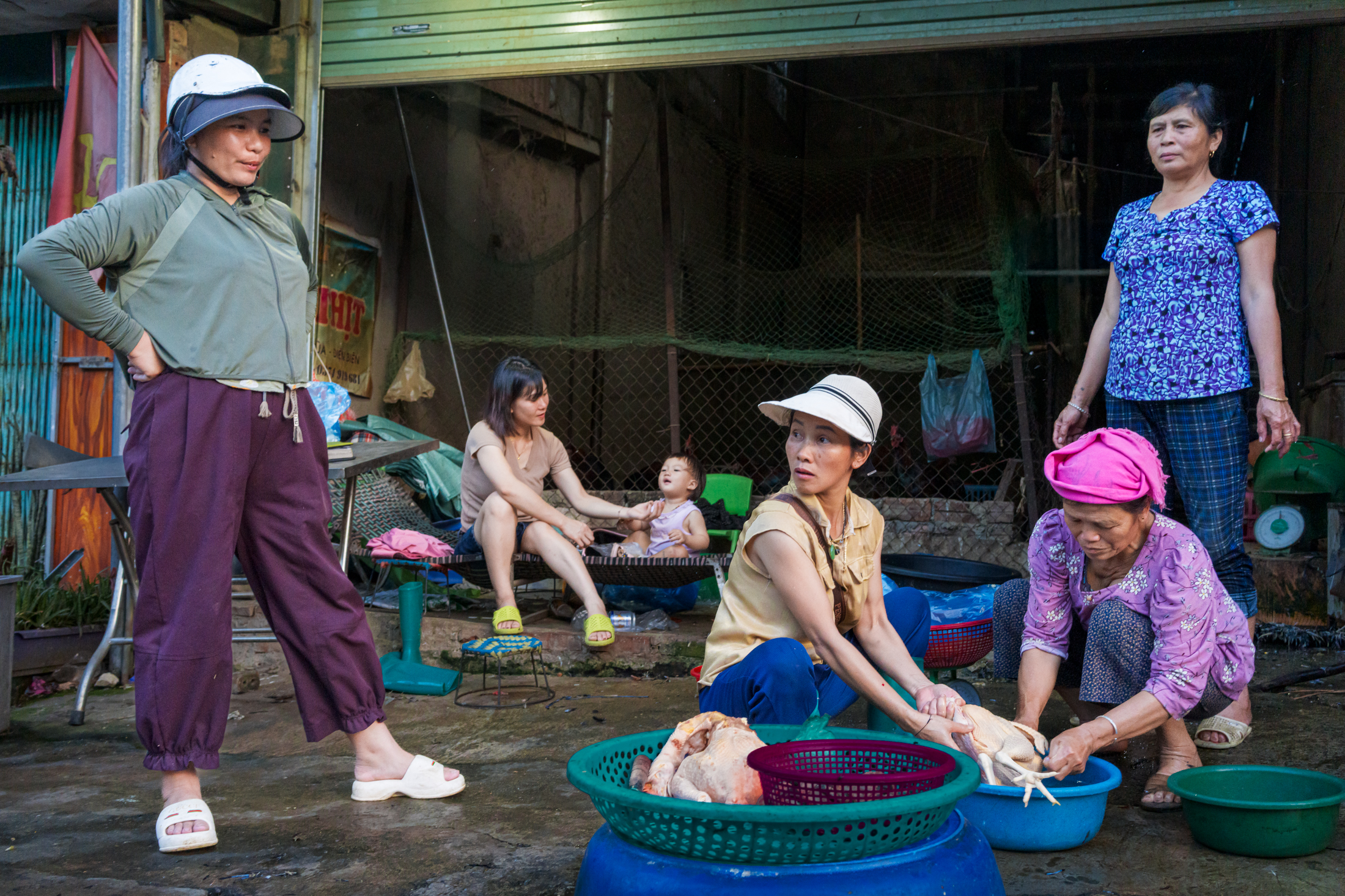 Northern Vietnam Photography: A Photographer’s Journey Beyond the Tourist Trail 9 Women prepare poultry outside a home in Hanoi, Vietnam, while family members gather nearby during the late afternoon.